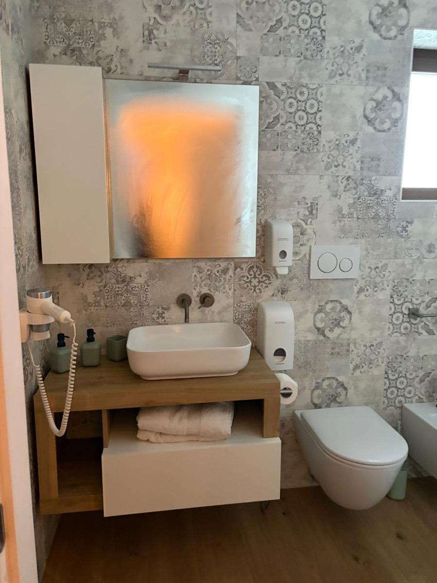 Bagno privato del B&B Villa Cassandra con lavabo d'appoggio su mensola in legno e asciugacapelli