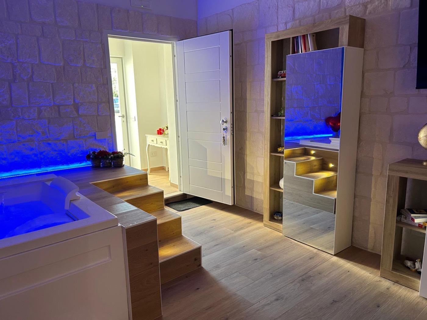 Ambiente della Junior Suite Deluxe con vasca idromassaggio, pareti in pietra e pavimento in rovere